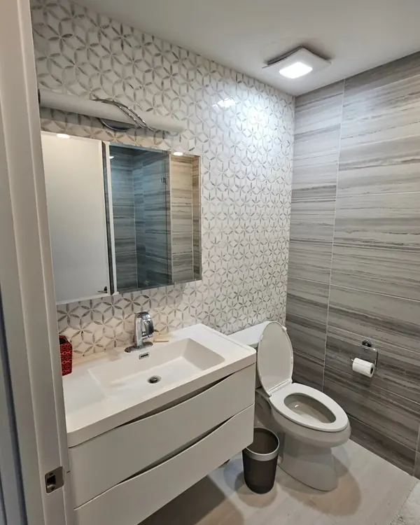 Bathroom with a floating white vanity, a mosaic accent wall and grey linear tile