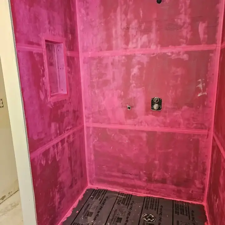 Pink waterproofing membrane over the shower walls, niche and floor