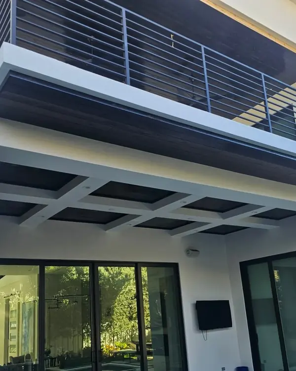 Dark-stained wood ceiling under the balcony of a modern white home