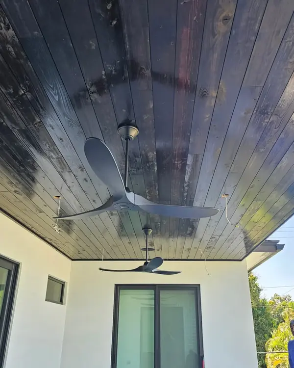 Covered patio with a dark-stained tongue-and-groove wood ceiling and ceiling fans