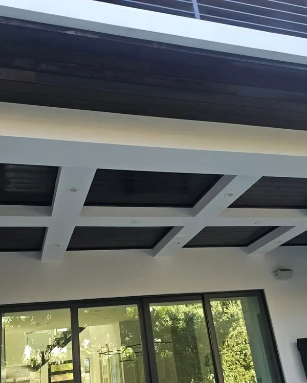 Dark-stained wood ceiling under the overhang of a modern white home