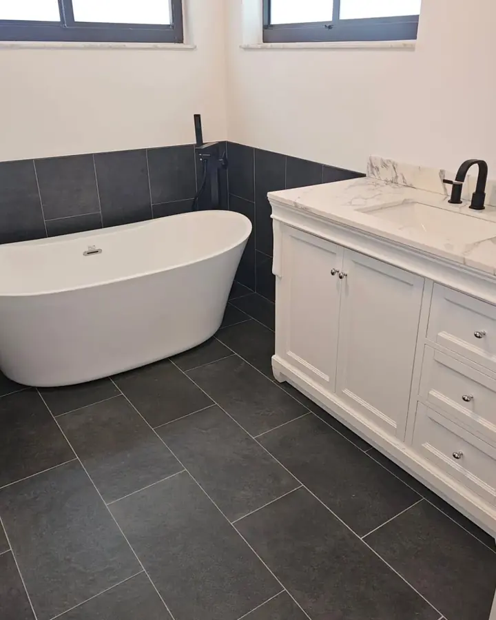 Finished bathroom with a freestanding tub, a white vanity and dark tile floors