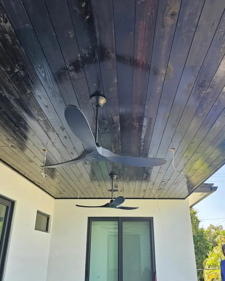 Covered patio with a dark-stained tongue-and-groove wood ceiling and ceiling fans
