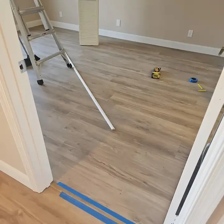 New wood-look plank floor in a bedroom, with a ladder and trim pieces on it