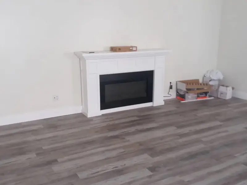 White fireplace surround over new wood-look plank floors
