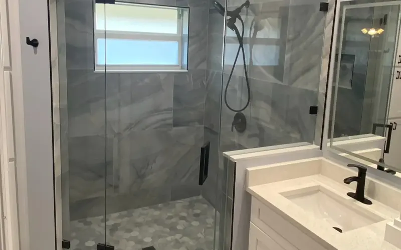 Finished bathroom with a frameless glass walk-in shower, grey tile and black fixtures