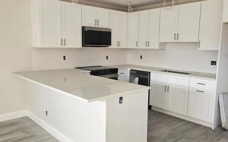 Finished white kitchen with shaker cabinets, white countertops and a peninsula