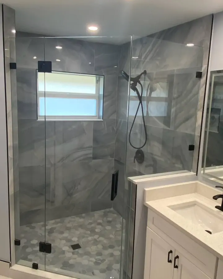 Finished bathroom with a frameless glass walk-in shower, grey tile, black fixtures and a white vanity