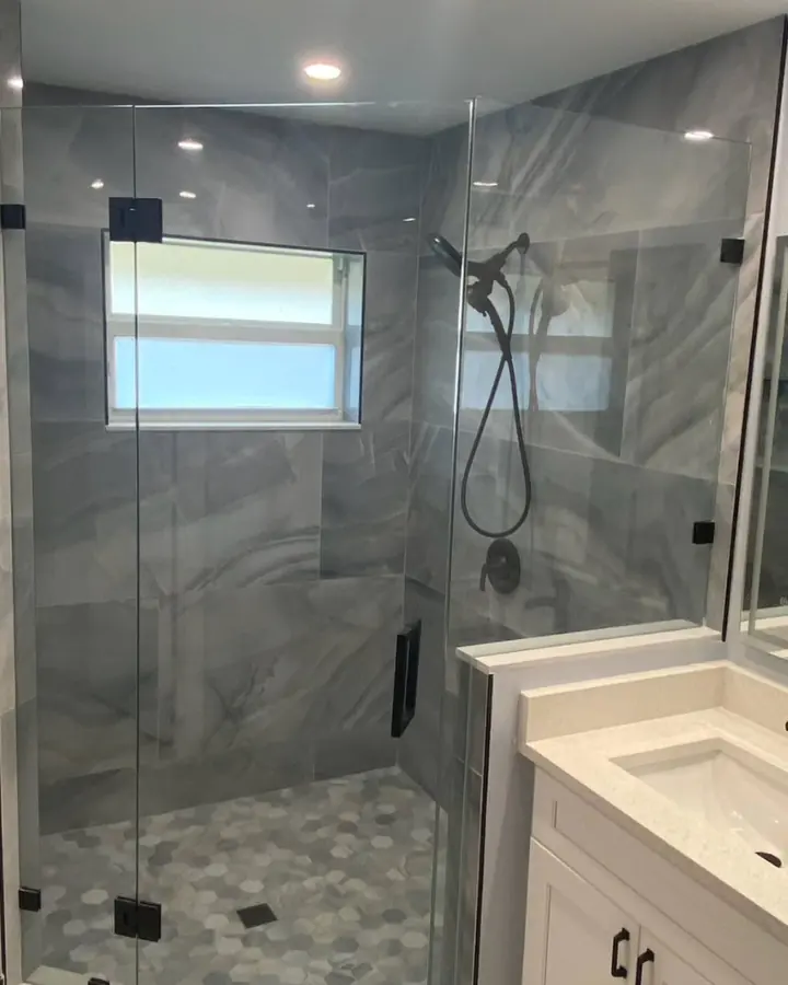 Finished bathroom with a frameless glass walk-in shower, grey tile, black fixtures and a white vanity