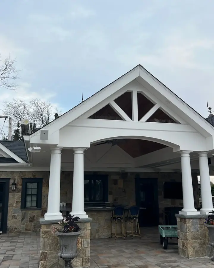 Covered front porch with a gable roof and white columns on a stone house