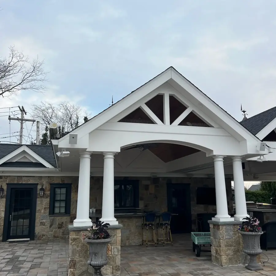 Covered front porch with a gable roof and white columns on a stone house