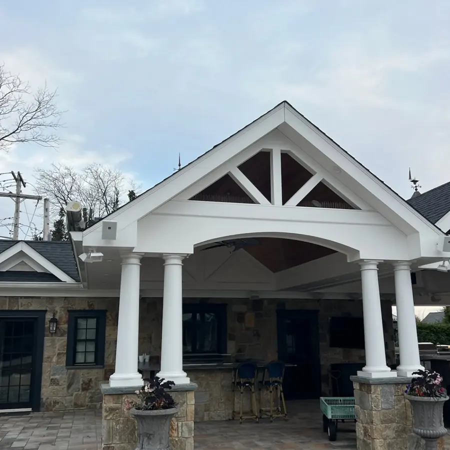 Covered front porch with a gable roof and white columns on a stone house