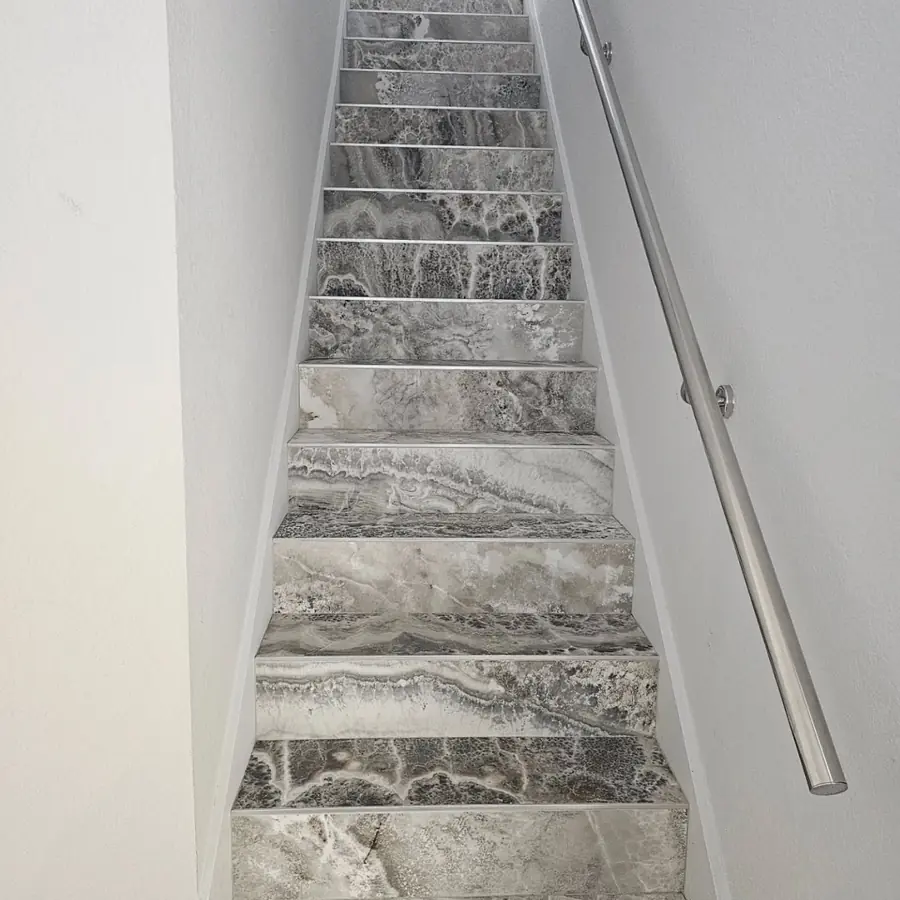 Staircase with marble-look tile treads and a steel handrail