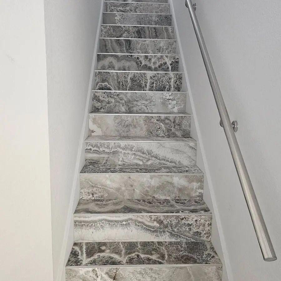 Staircase with marble-look tile treads and a steel handrail