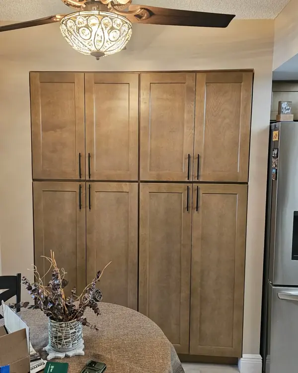 Tall stained shaker pantry cabinets beside the refrigerator