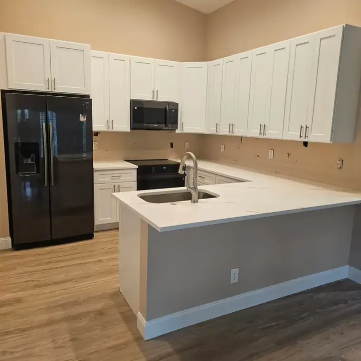 Finished white kitchen with black appliances, white countertops and a grey peninsula